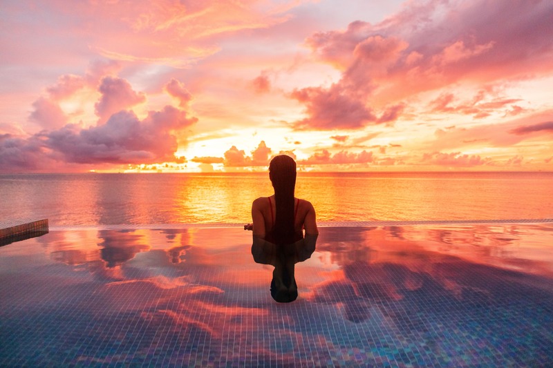 girl looking at ocean sunset in infinity pool